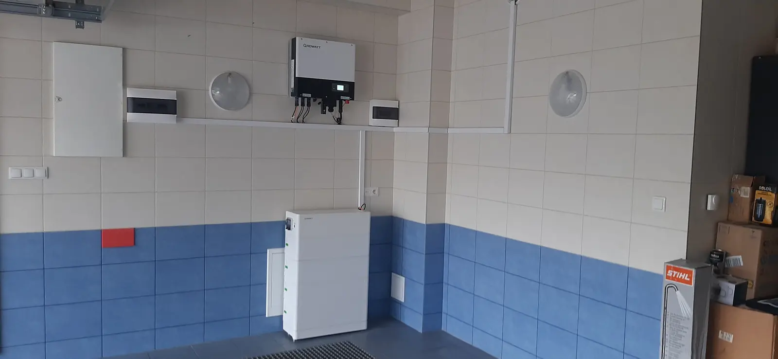 Falownik fotowoltaiczny i skrzynki elektryczne na ścianie pomieszczenia gospodarczego