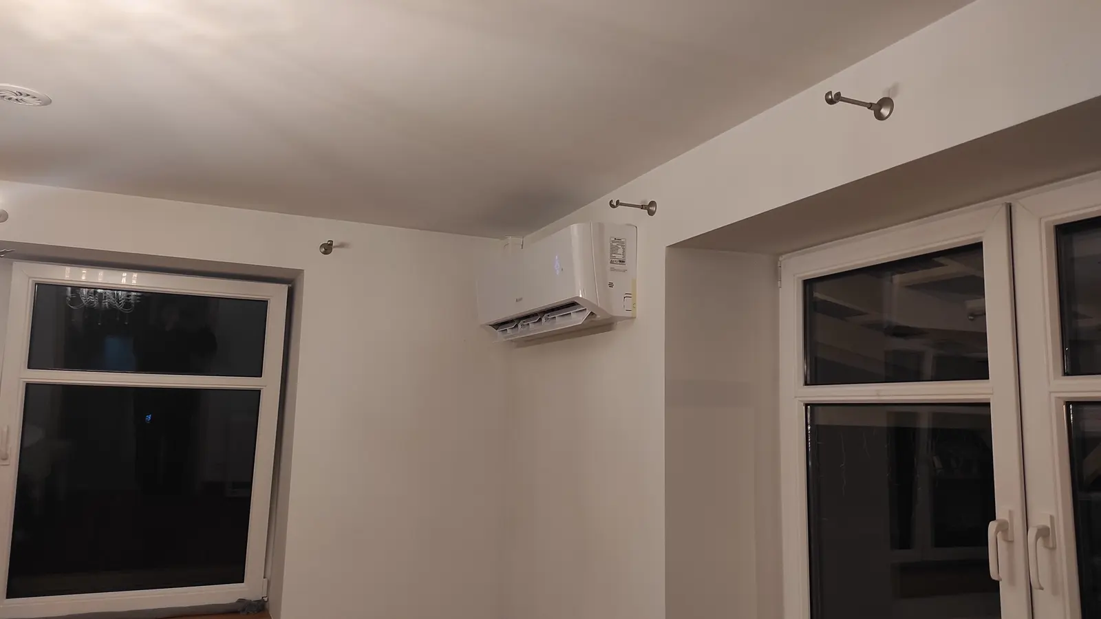 Klimatyzator ścienny między oknem a drzwiami tarasowymi w pokoju bez wykończenia